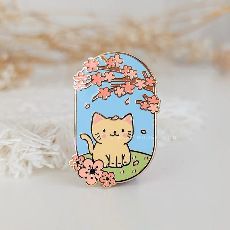 cat sitting under sakura blossoms enamel pin
