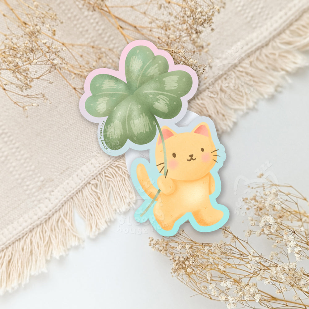 Sticker of a cat holding a four-leaf clover.