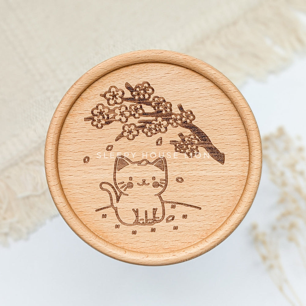 Wooden coaster with a cat and cherry blossom design on a beige background