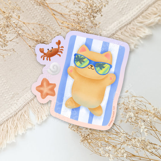 Sticker with a cartoon cat wearing sunglasses on a blue and white striped beach towel