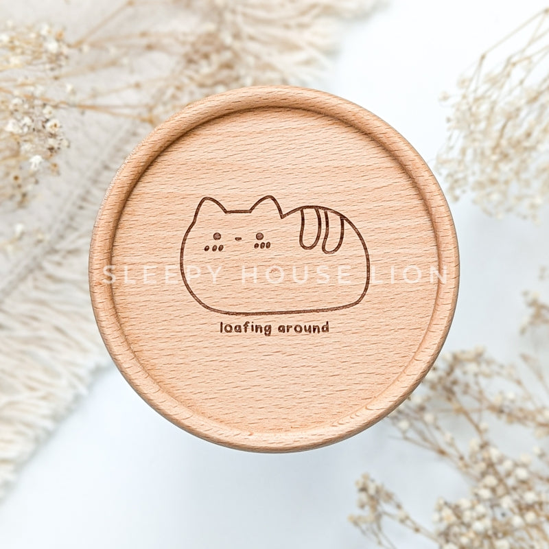 wooden engraved coaster of cat in the shape of a bread loaf with text: loafing around