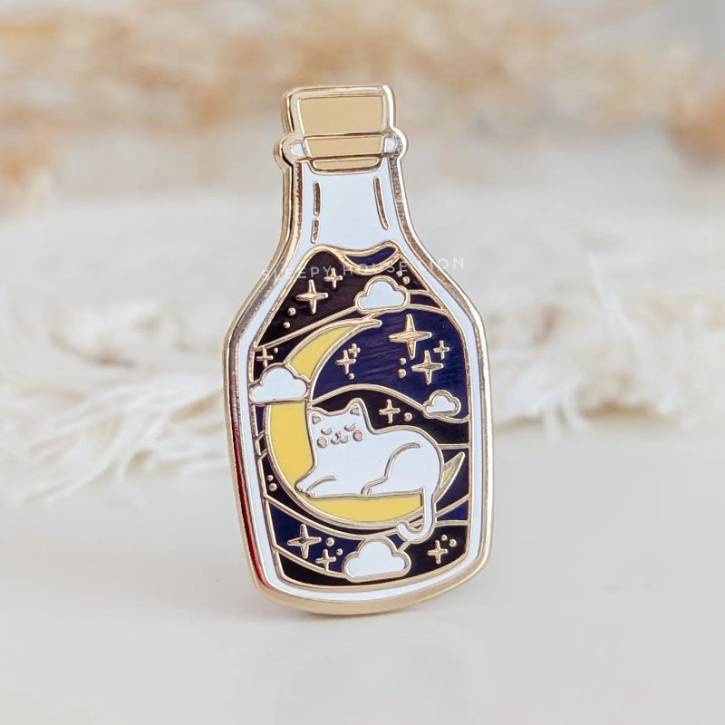 cat sitting on a moon in a bottle enamel pin