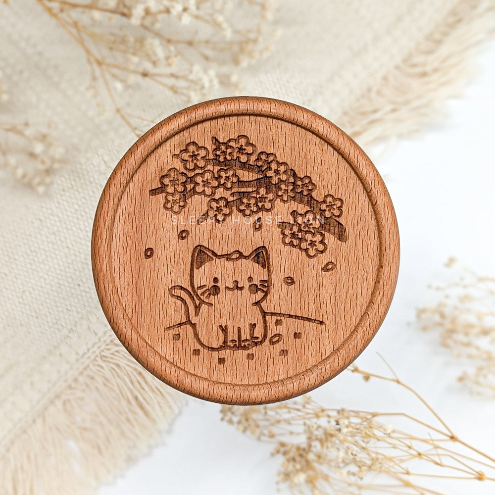 Wooden coaster with a cat and cherry blossom design on a light background