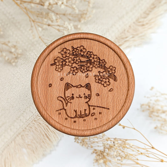 Wooden coaster with a cat and cherry blossom design on a light background