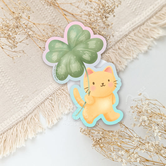 Sticker of a cat holding a four-leaf clover.