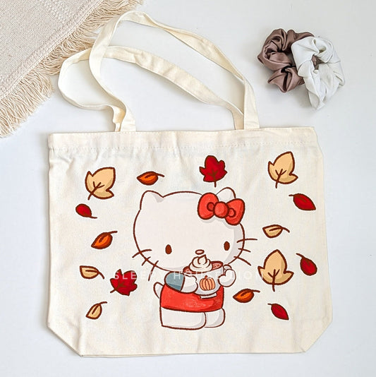 Tote bag with a cartoon cat holding a pumpkin and autumn leaves on a light background