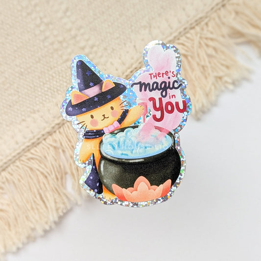 Decorative sticker with a cat in a witch hat and a pot of gold, on a textured surface.