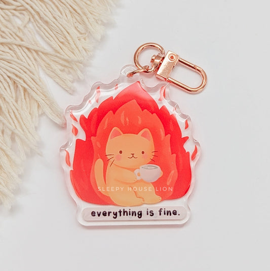 Keychain with a cat design and 'everything is fine' text on a soft background