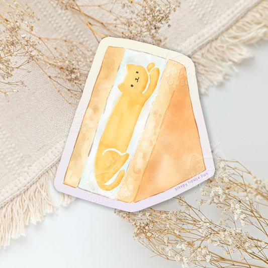Sticker with a yellow cat mango sando on a textured surface with dried flowers