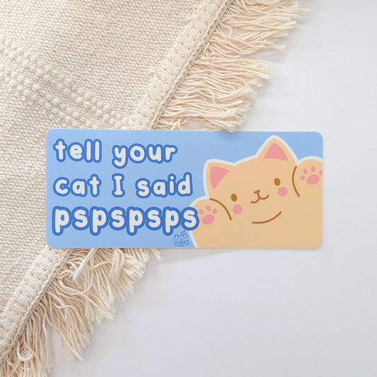 Sticker with a cat illustration and text "Tell Your Cat I said pspspsps" on a textured surface