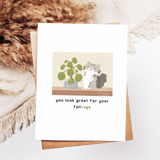 Greeting card with a cartoon cat and plant illustration on a textured surface